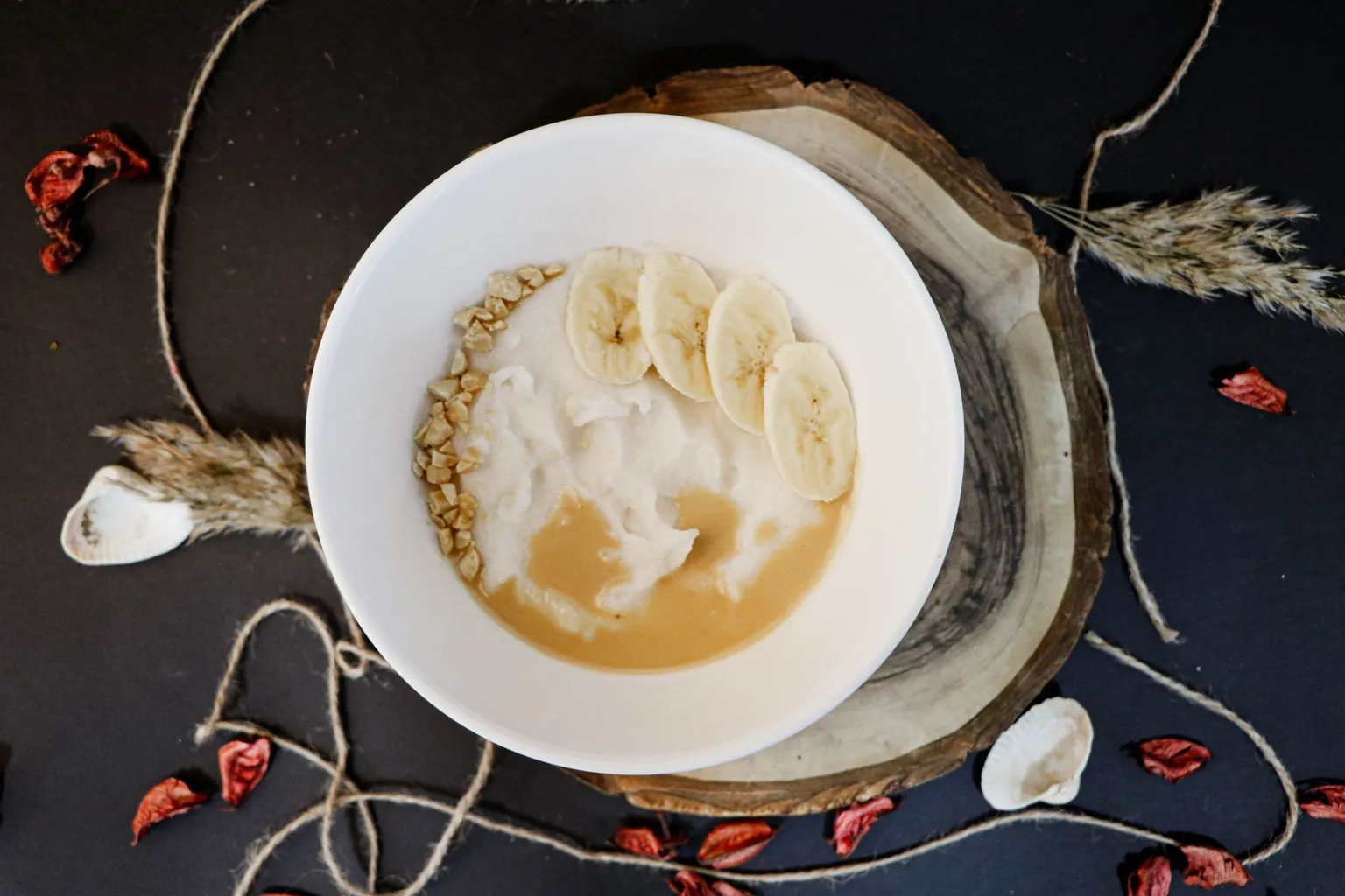 Bol de bouillie de céréales garnie de rondelles de banane, de purée d'oléagineux et d'éclats de cacahuète