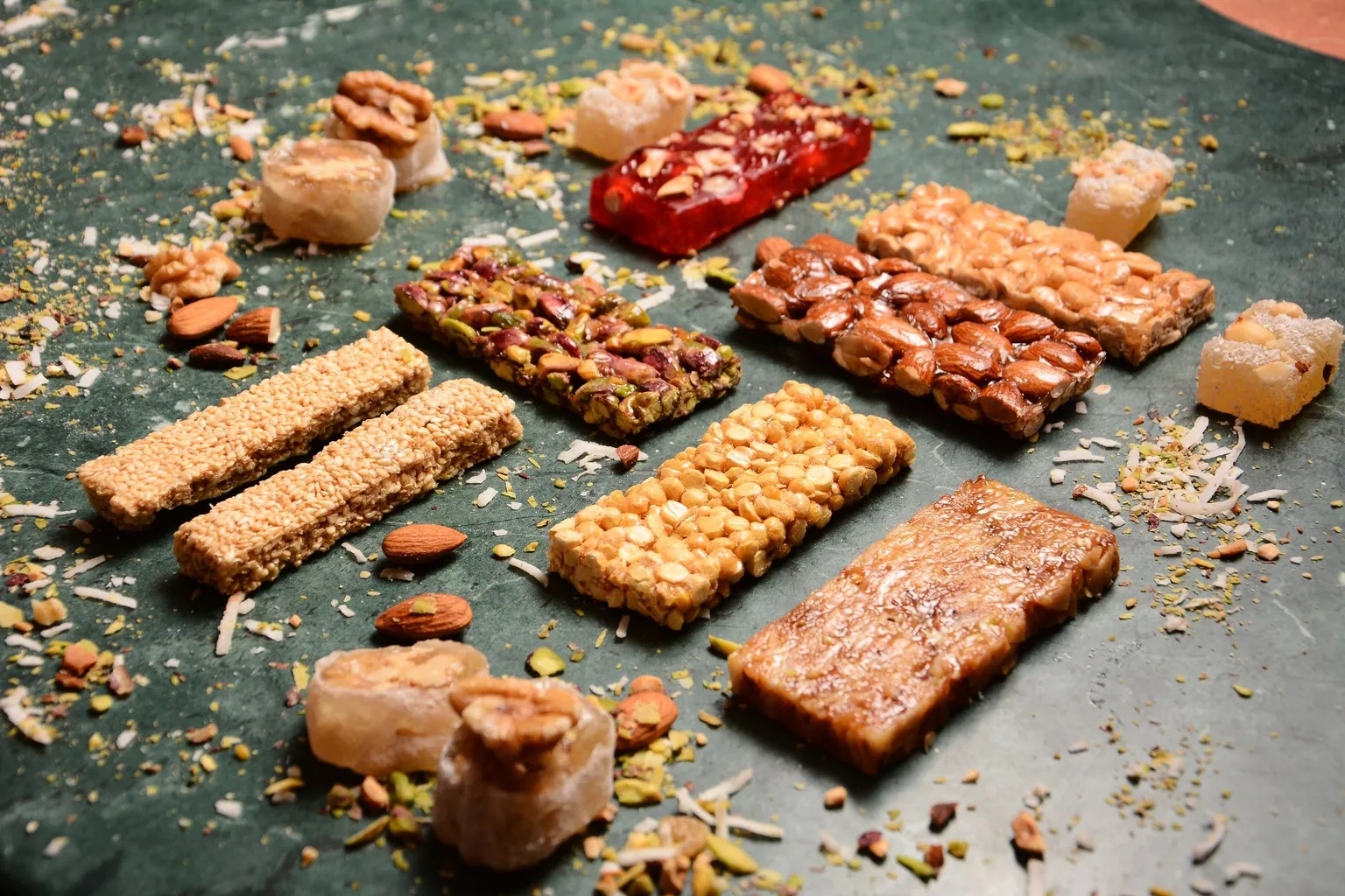 Barres de graines, d'amandes, de pistaches et de cacahuètes posées sur un plan de travail en marbre vert