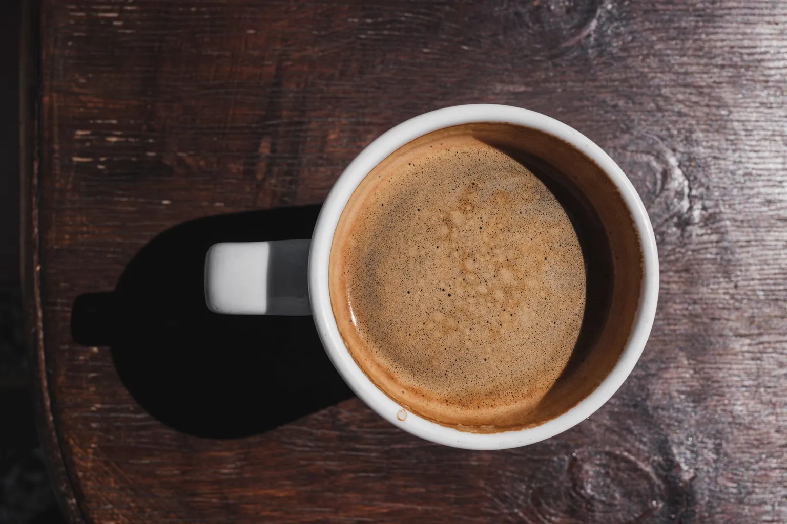 Tasse blanche de café mousseux vue de dessus sur une table en bois sombre