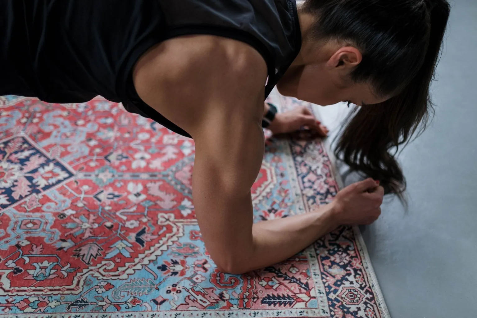 Femme en appui sur les avant-bras sur un tapis à motifs, vue de près pendant une planche