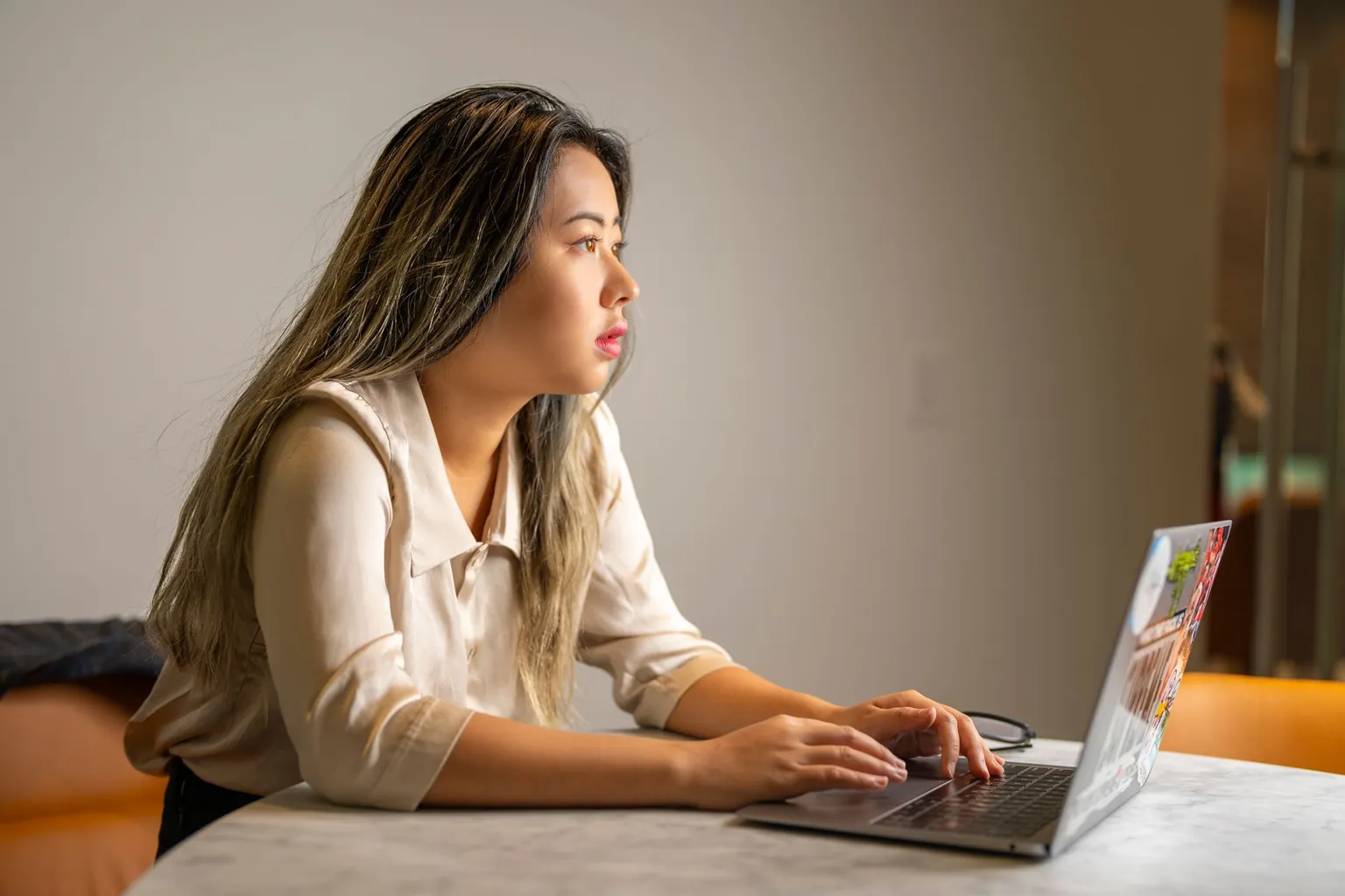 Jeune femme concentrée qui tape sur un ordinateur portable posé sur une table en marbre
